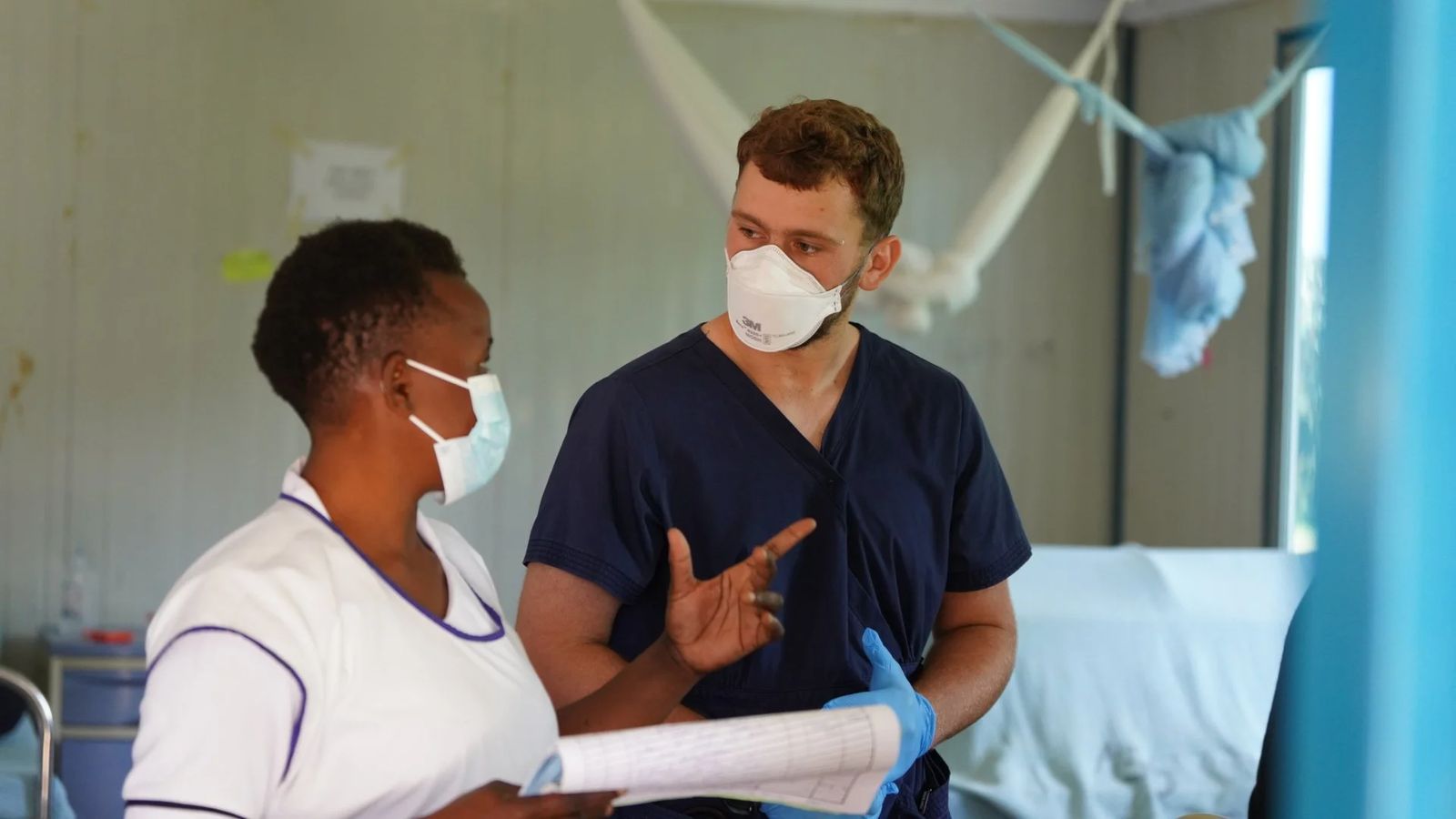 A nurse and a caregiver talking through a patient chart