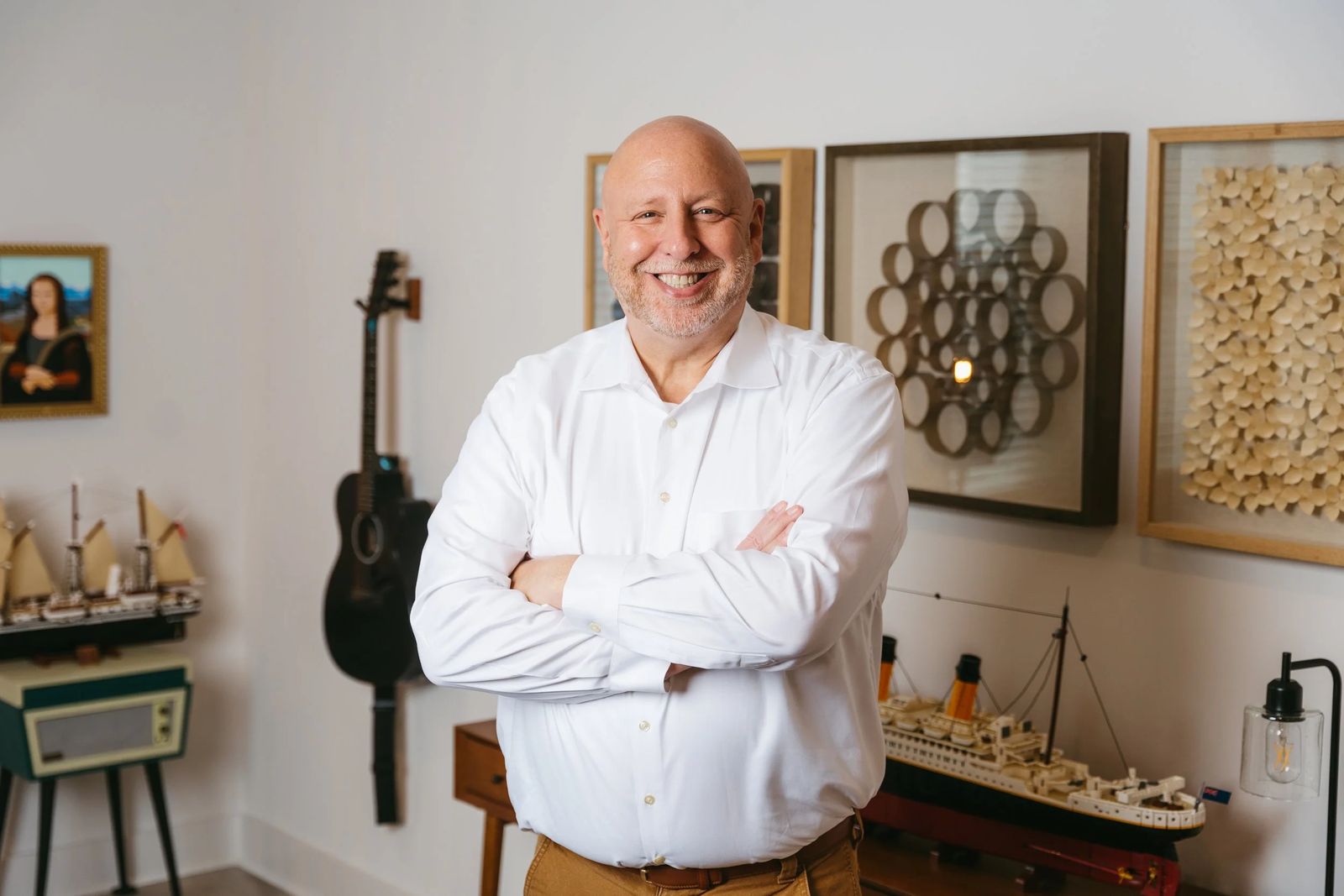 A smiling agent standing with arms crossed in a styled room