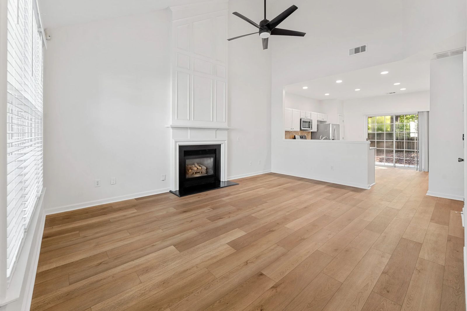A bright living room with a fireplace and open kitchen