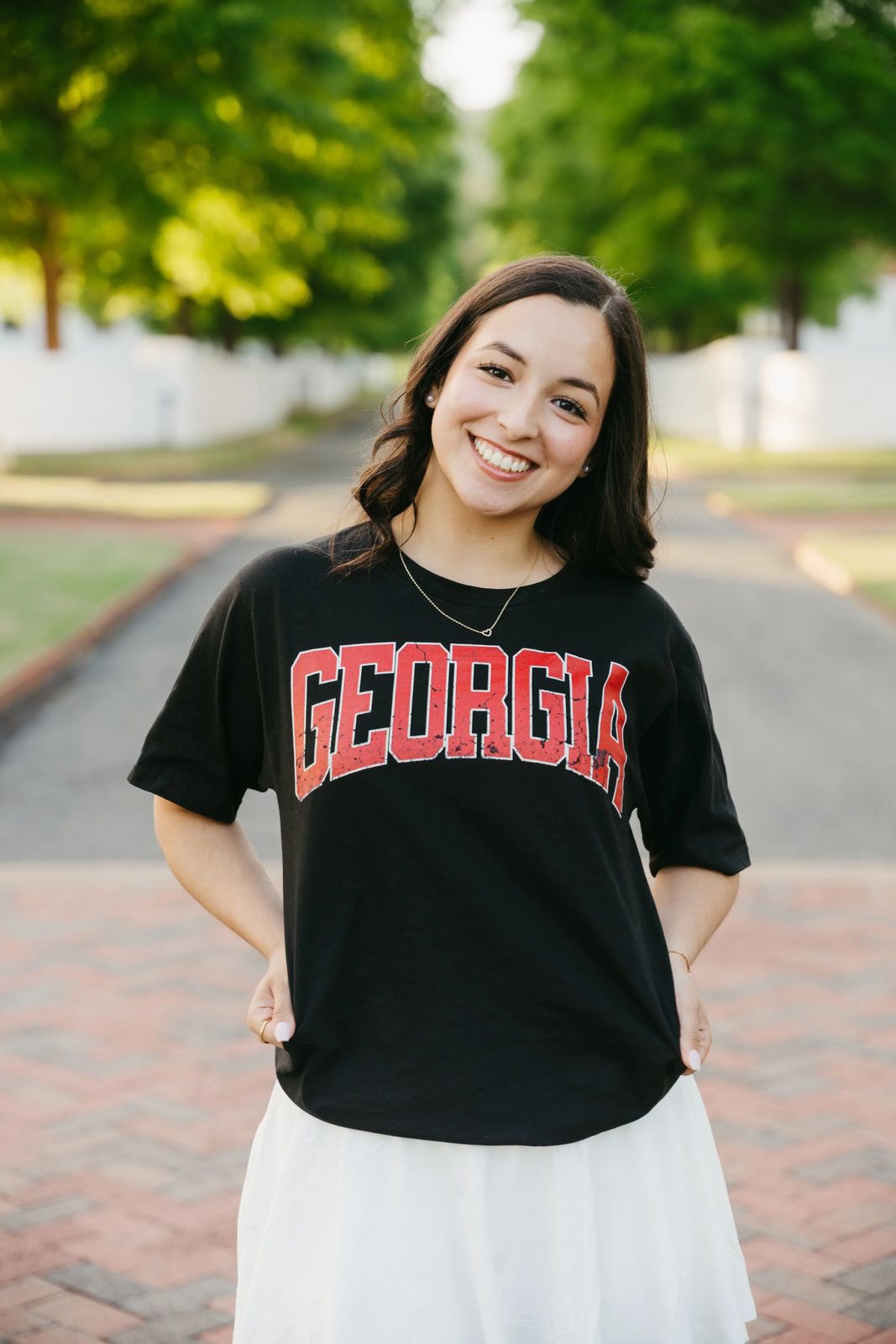 A senior smiling on a brick path