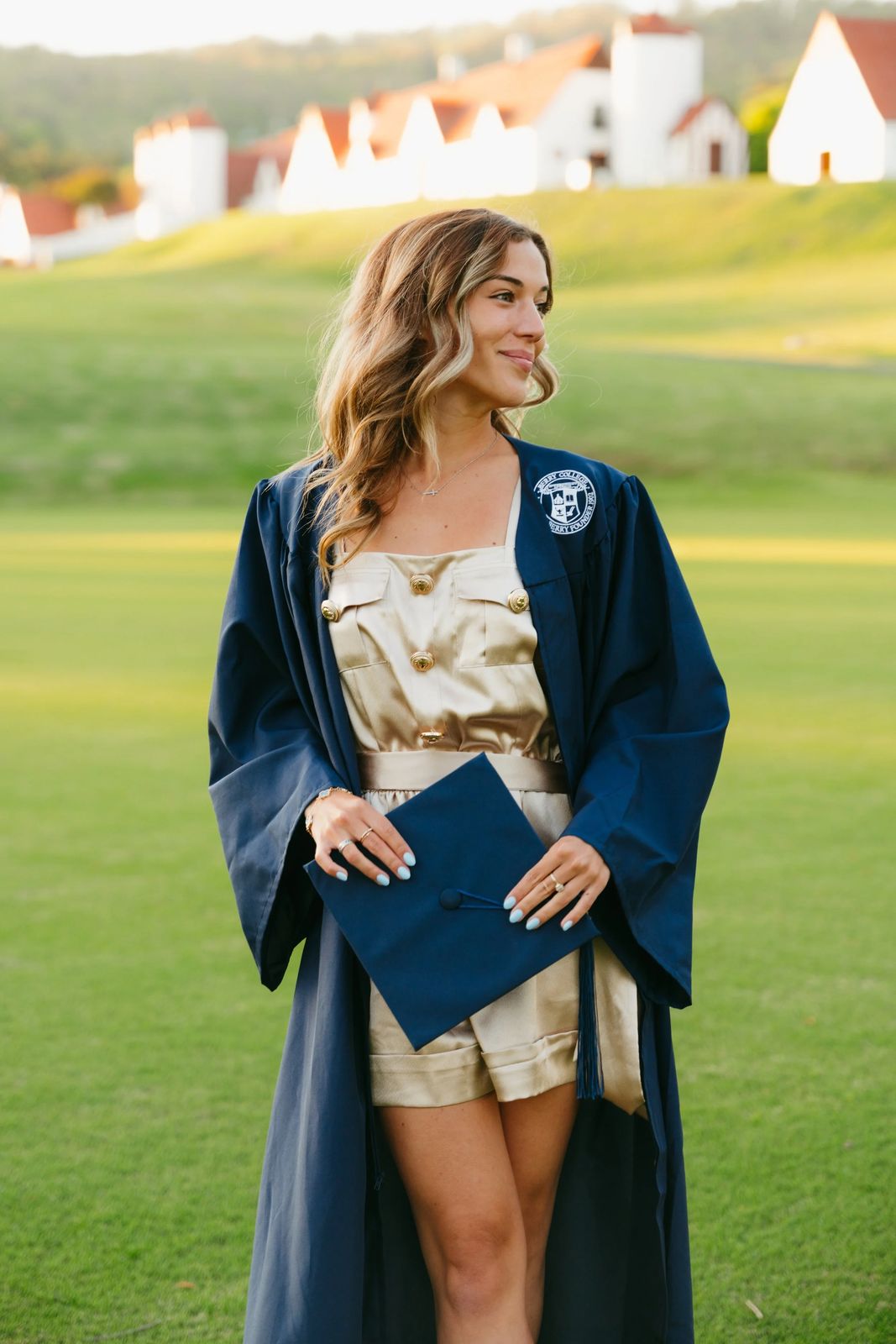 A senior in her gown on a green hillside