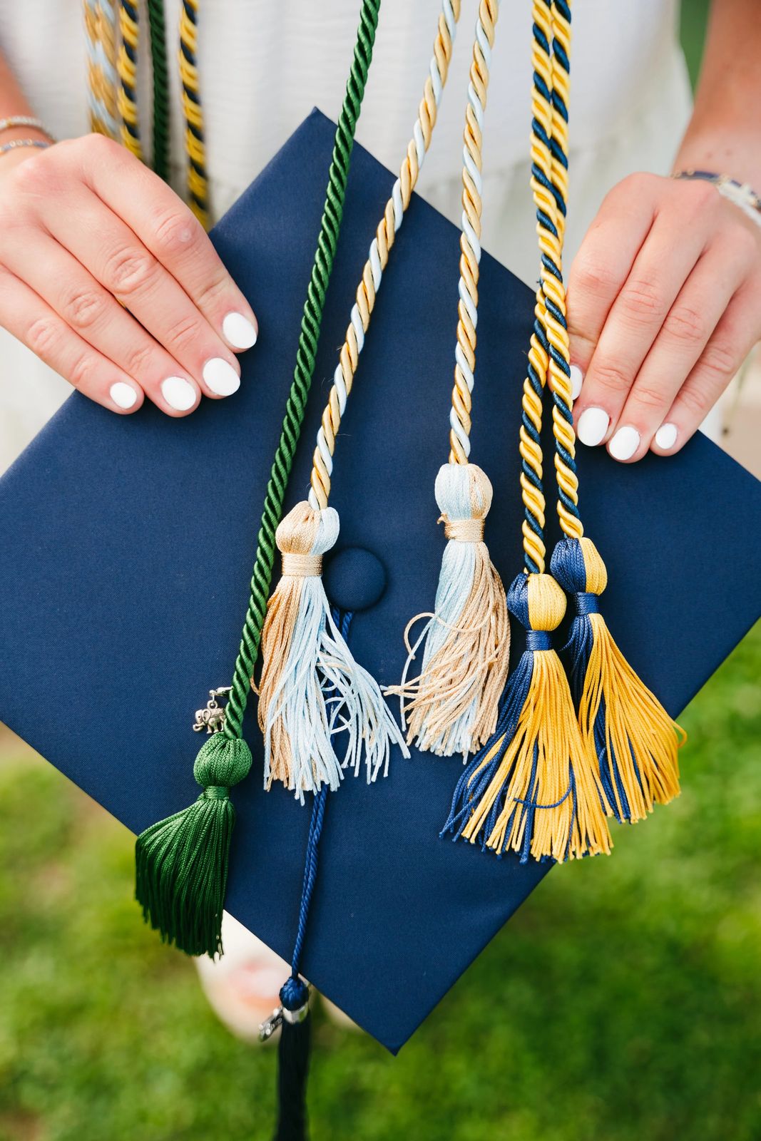Hands holding a graduation cap with cords