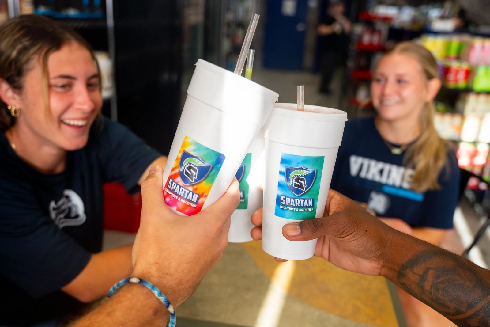 Two friends toasting with Spartan Smoothies cups