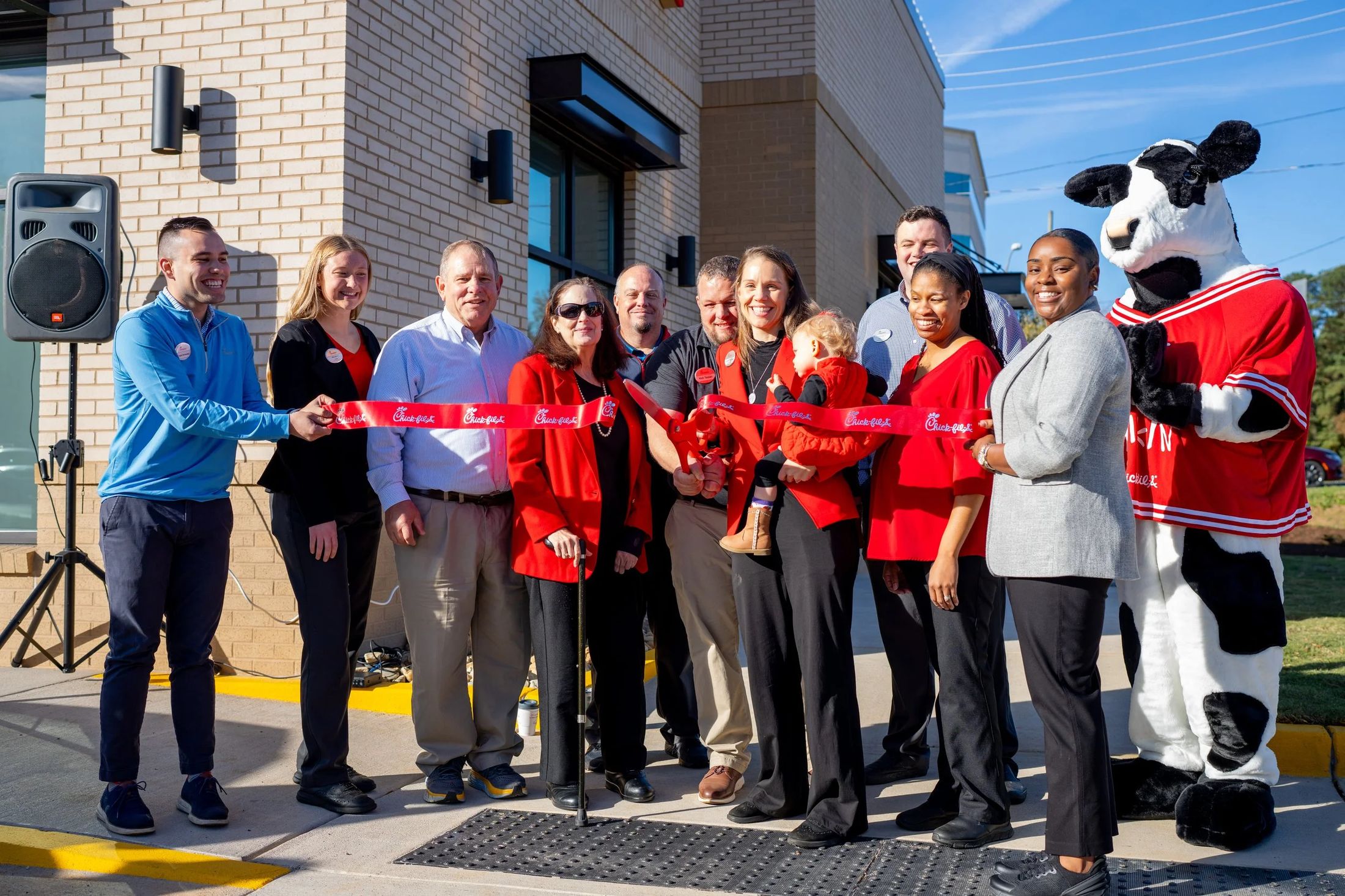 A Chick-fil-A grand opening ribbon cutting with the team and mascot